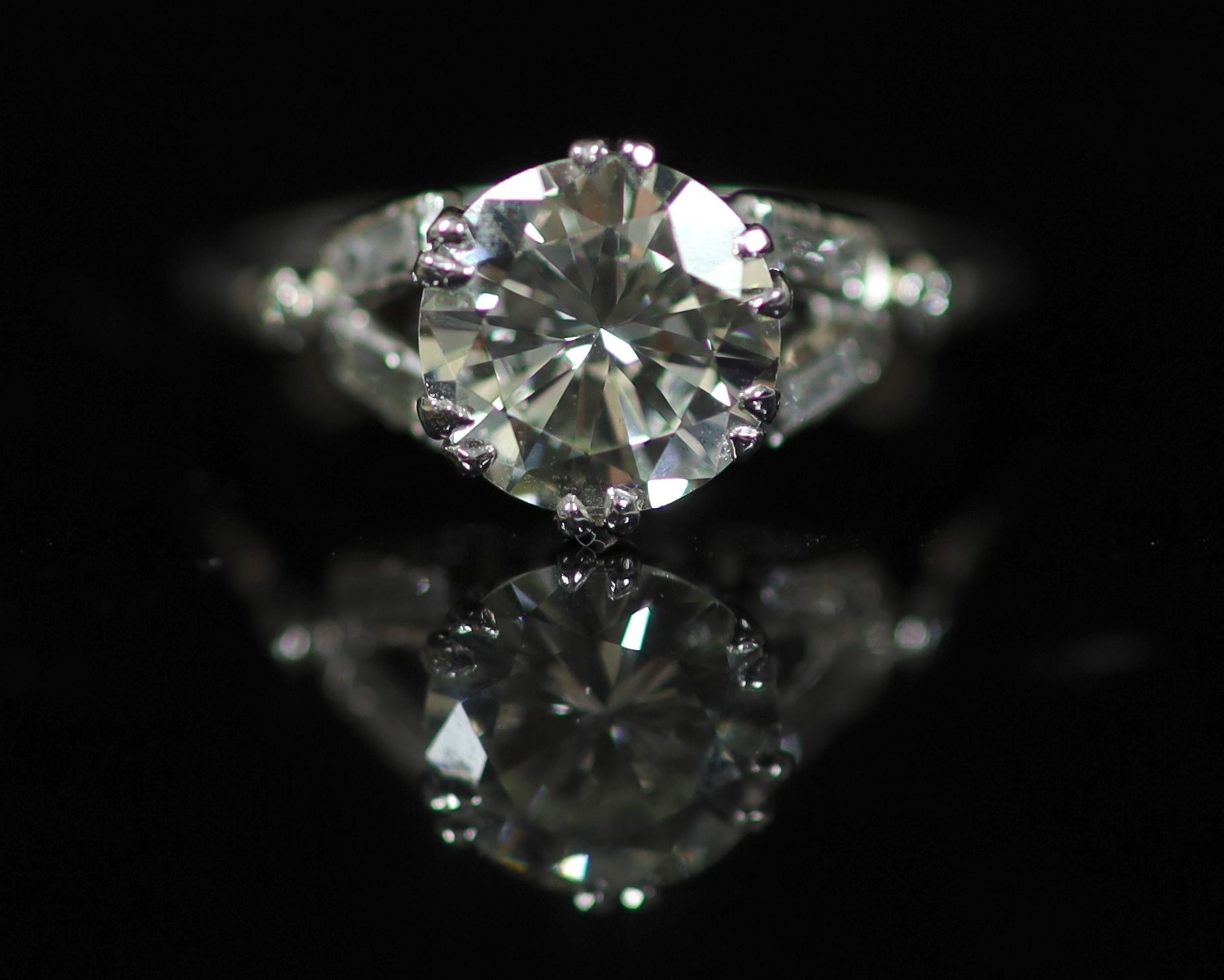 A platinum and single stone diamond ring, with baguette and diamond chip set shoulders